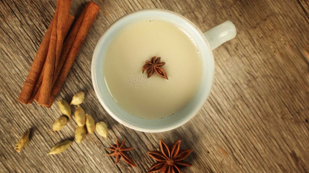 cinnamon tea in a glass cup, cinnamon sticks, cardamom, anise