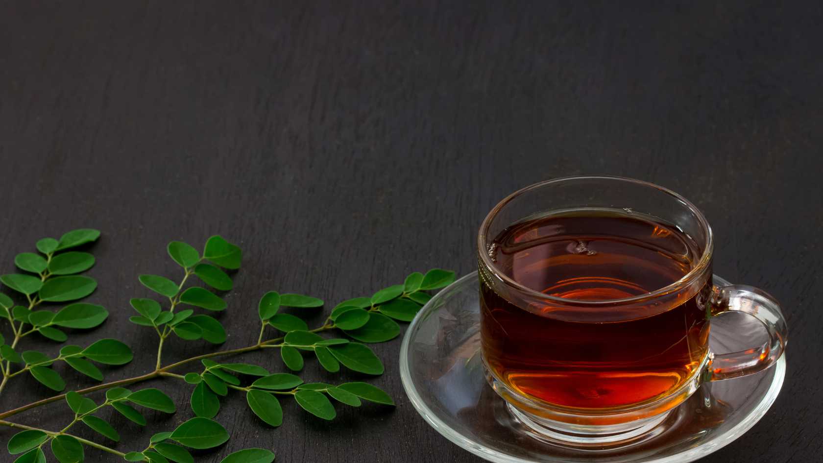 moringa leaves and moringa tea in a glass cup